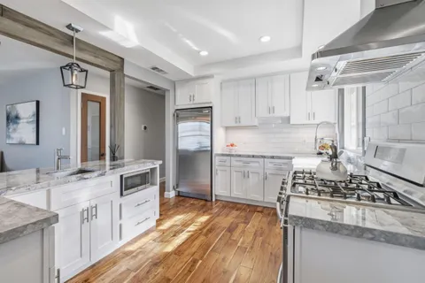 a kitchen with kitchen island granite countertop a sink cabinets and stainless steel appliances