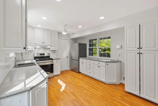 a kitchen with granite countertop a sink stainless steel appliances and cabinets