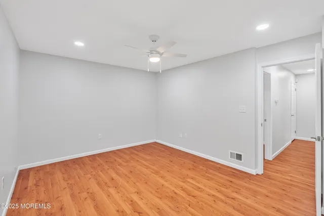 an empty room with wooden floor and fan