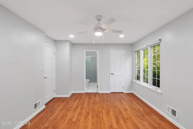 a view of empty room with wooden floor and fan