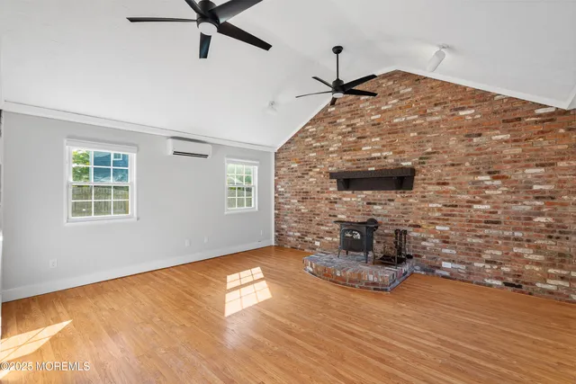 a view of a livingroom with wooden floor a ceiling fan and windows