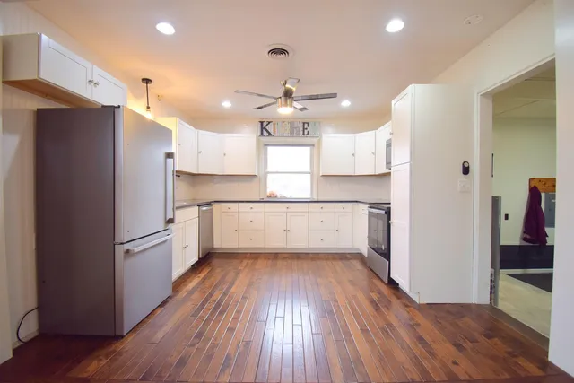 a kitchen with granite countertop a refrigerator and a wooden floor