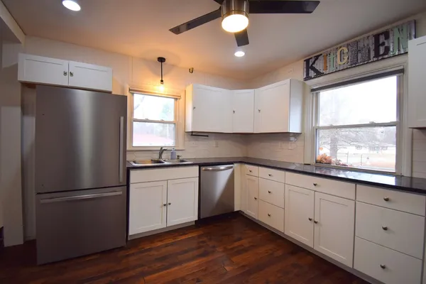 a kitchen with granite countertop stainless steel appliances a refrigerator cabinets and a window