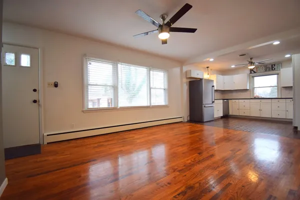 a view of an empty room with window and wooden floor