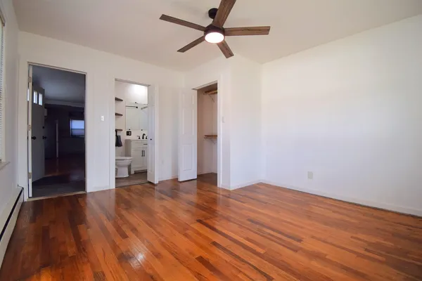 an empty room with wooden floor and ceiling fan