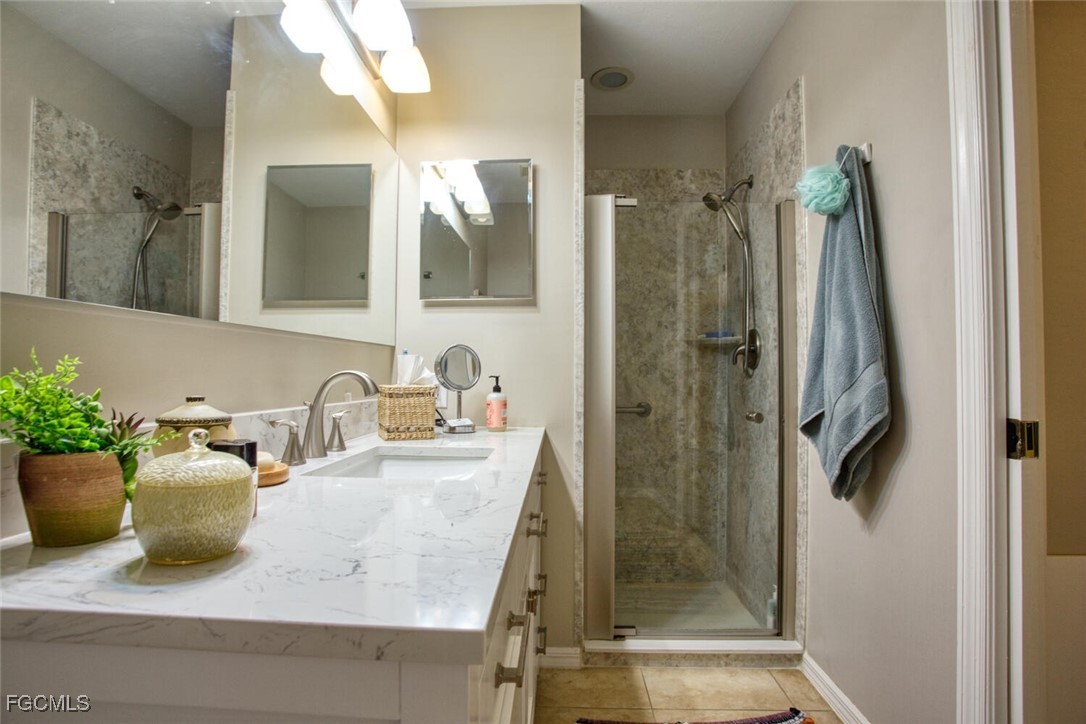 8076 Queen Palm Lane, Unit 416 Fort Myers, FL 33966 - Photo 17 of 18 a bathroom with a granite countertop sink a mirror and shower