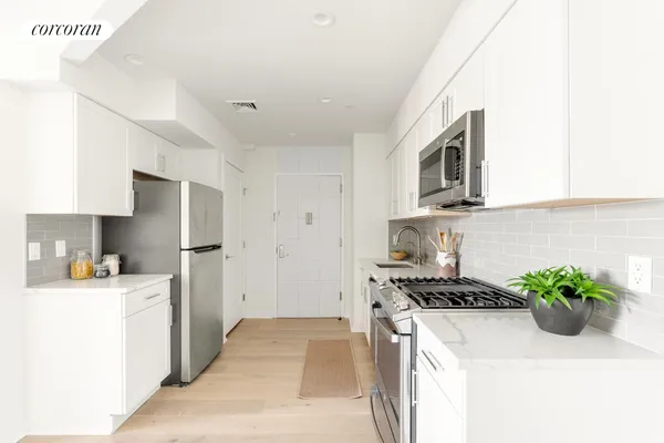 a kitchen with stainless steel appliances a sink a stove a microwave a refrigerator a sink and cabinets