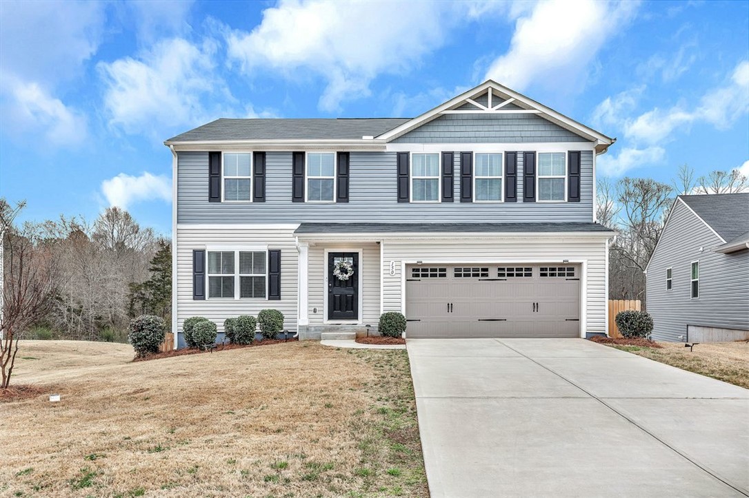 This two-story residence presents a classic facade with a welcoming entrance and ample driveway space.