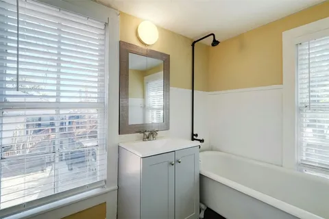a bathroom with a tub sink shower and a mirror