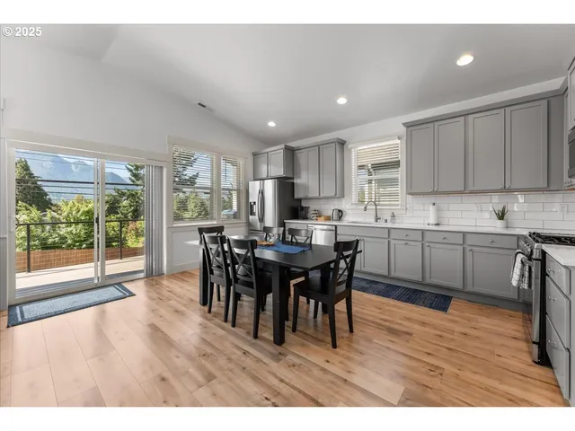 a open kitchen with granite countertop a dining table chairs and white cabinets