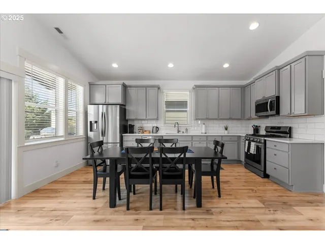 a open kitchen with stainless steel appliances granite countertop a refrigerator a stove a sink a dining table and chairs