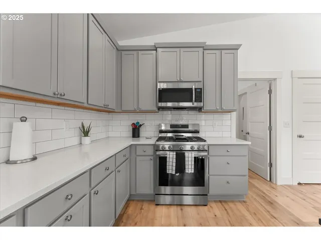 a kitchen with stainless steel appliances a stove a sink a stove and white cabinets