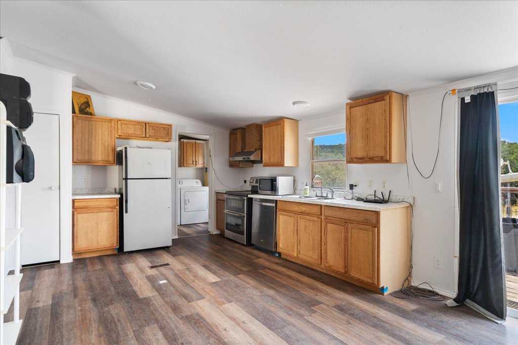 10500 Tarantula Court Leander, TX 78641 - Photo 6 of 34 a kitchen with a refrigerator a stove top oven a sink and dishwasher with wooden floor
