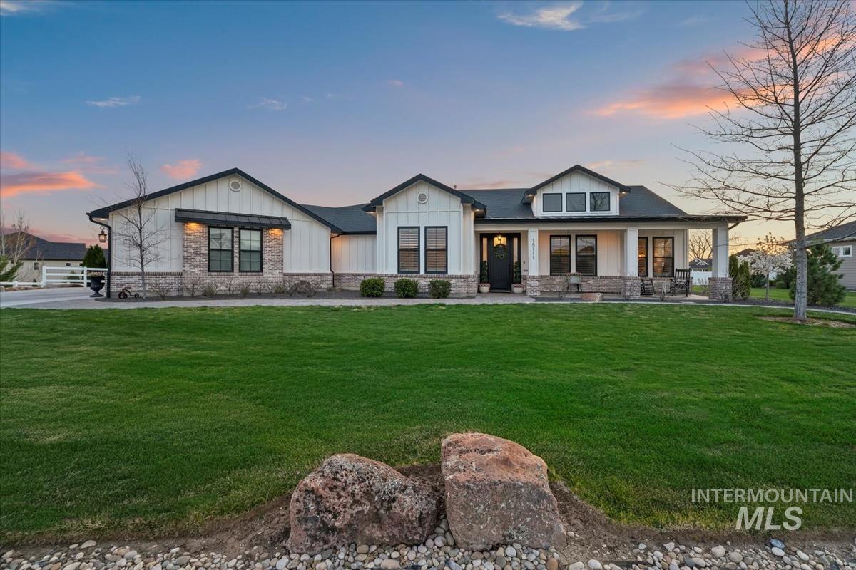 15111 Pinehurst Way Caldwell, ID 83607 - Photo 1 of 43 View of front of house featuring board and batten siding, a front yard, a porch, and stone siding