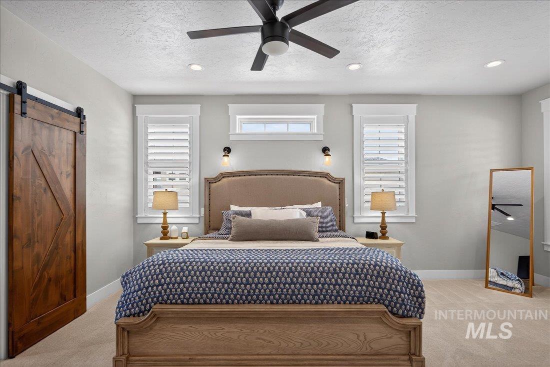 15111 Pinehurst Way Caldwell, ID 83607 - Photo 12 of 43 Bedroom with a barn door, light colored carpet, ceiling fan, recessed lighting, and a textured ceiling