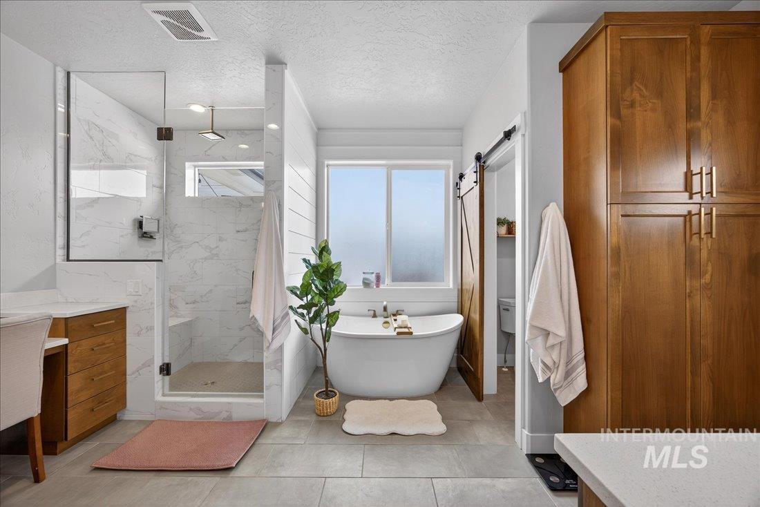 15111 Pinehurst Way Caldwell, ID 83607 - Photo 13 of 43 Bathroom with a marble finish shower, vanity, a freestanding bath, and a textured ceiling