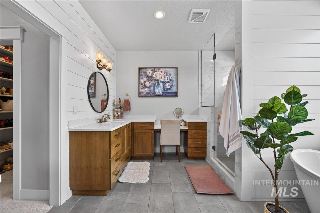 15111 Pinehurst Way Caldwell, ID 83607 - Photo 14 of 43 Bathroom featuring wood walls, vanity, a shower stall, a spacious closet, and a freestanding bath