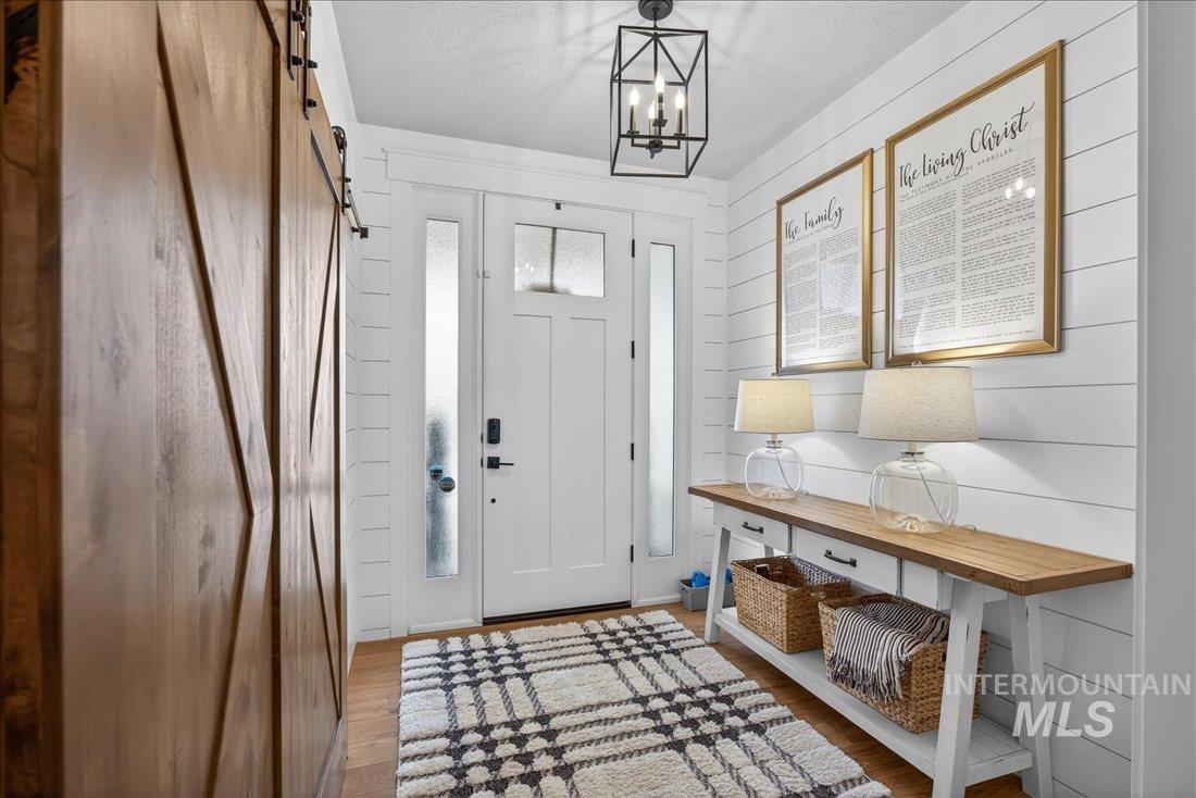 15111 Pinehurst Way Caldwell, ID 83607 - Photo 2 of 43 Entrance foyer with a barn door, wood finished floors, suspended lighting, wood walls, and a textured ceiling