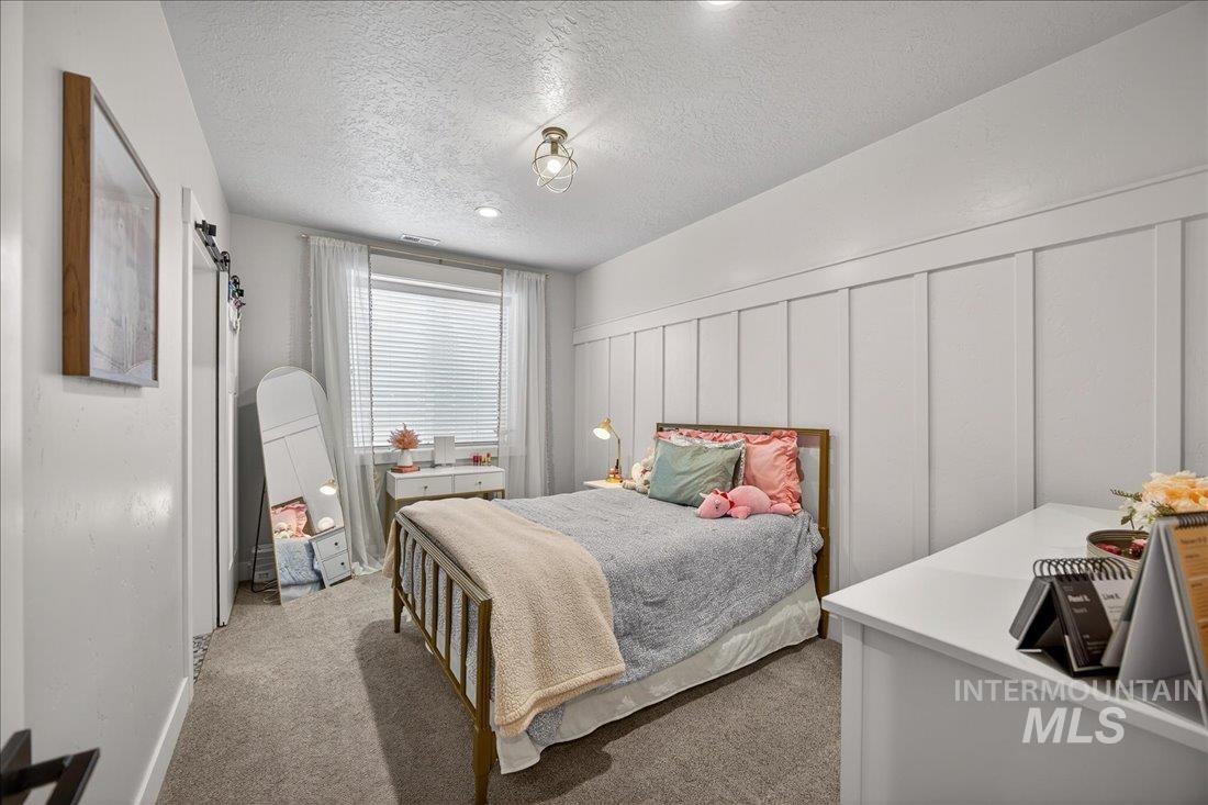 15111 Pinehurst Way Caldwell, ID 83607 - Photo 26 of 43 Bedroom with a decorative wall, carpet flooring, a textured ceiling, and a wainscoted wall