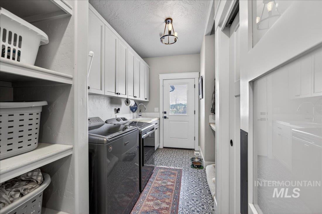 15111 Pinehurst Way Caldwell, ID 83607 - Photo 31 of 43 Laundry area with a textured ceiling, separate washer and dryer, dark floors, and cabinet space