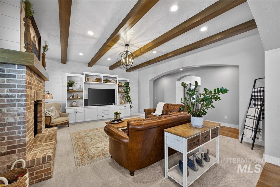 15111 Pinehurst Way Caldwell, ID 83607 - Photo 5 of 43 Living room with a fireplace, beamed ceiling, a chandelier, arched walkways, and wooden walls