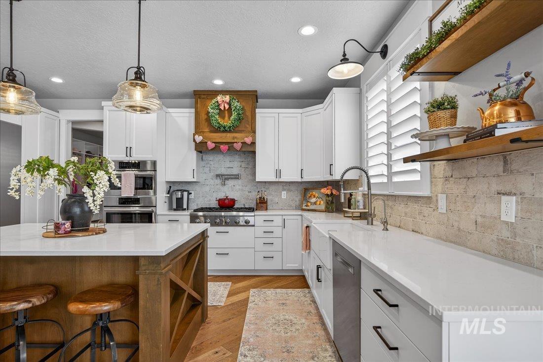 15111 Pinehurst Way Caldwell, ID 83607 - Photo 7 of 43 Kitchen with open shelves, white cabinetry, light wood-style floors, hanging light fixtures, and a breakfast bar area