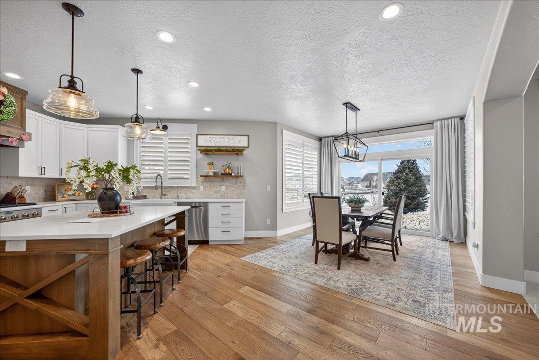 15111 Pinehurst Way Caldwell, ID 83607 - Photo 9 of 43 Kitchen featuring open shelves, a textured ceiling, light wood-style floors, a breakfast bar area, and light stone countertops
