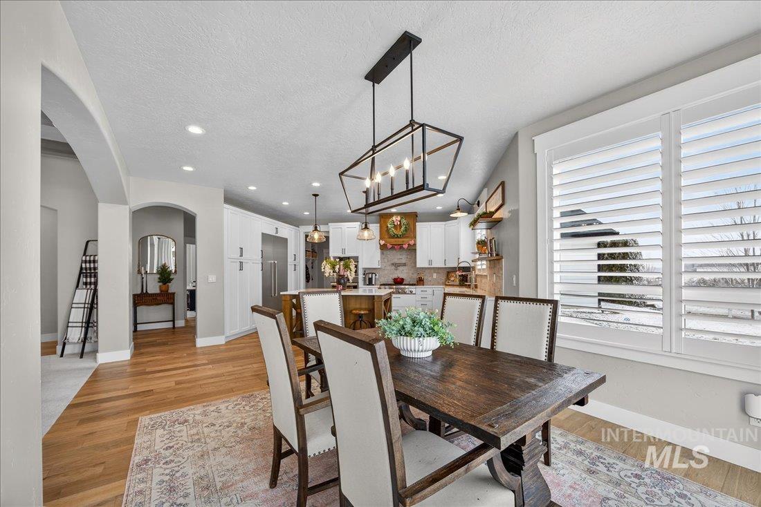 15111 Pinehurst Way Caldwell, ID 83607 - Photo 10 of 43 Dining space featuring arched walkways, light wood-style flooring, a textured ceiling, and suspended lighting