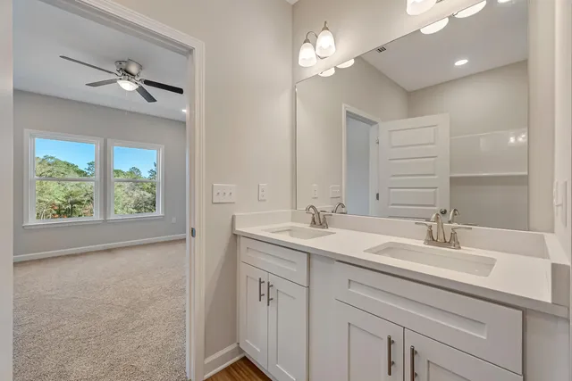 a bathroom with a double vanity sink a large mirror and a bathtub