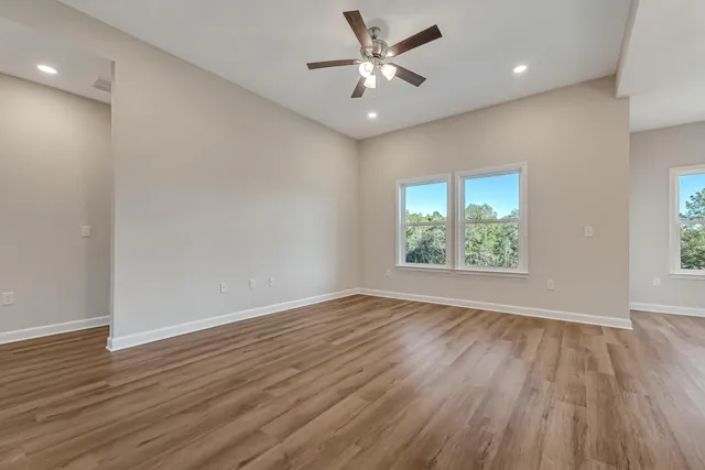 an empty room with wooden floor and windows