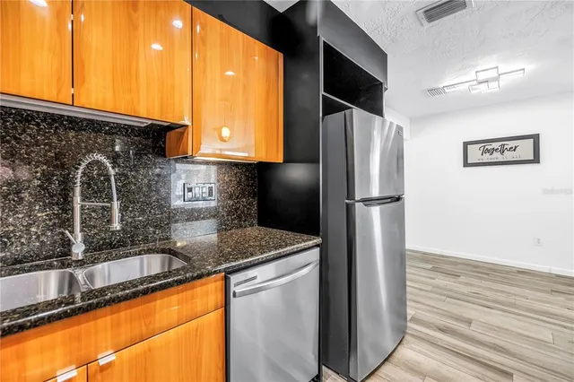 a kitchen with stainless steel appliances granite countertop a refrigerator and a sink