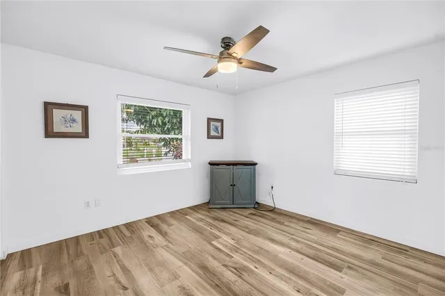 a view of empty room with wooden floor and fan