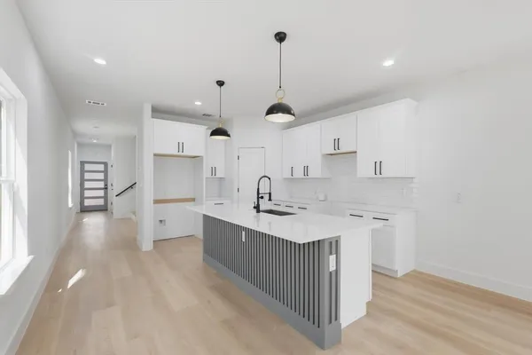 a kitchen with stainless steel appliances a sink a stove a refrigerator and white cabinets