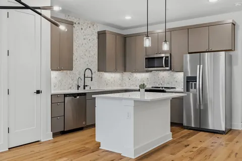 a kitchen with stainless steel appliances granite countertop a sink stove and refrigerator