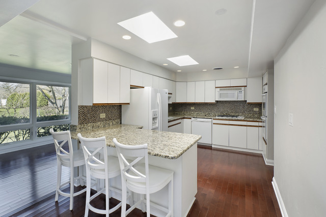 918 Lee Road Northbrook, IL 60062 - Photo 8 of 17 a kitchen with stainless steel appliances kitchen island granite countertop a stove a refrigerator a sink a dining table and chairs with wooden floor