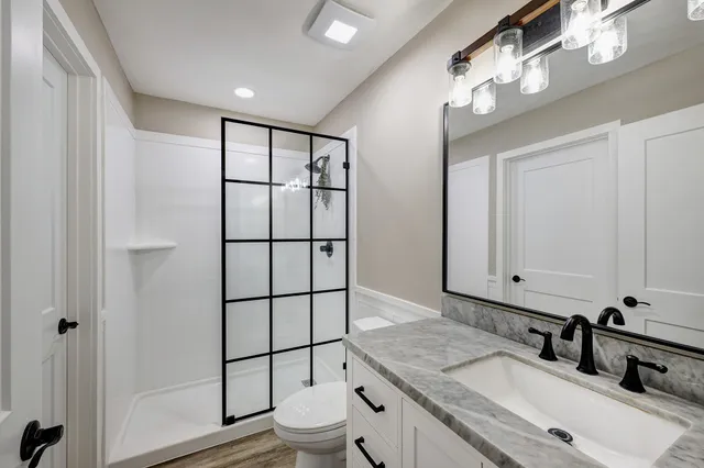 a bathroom with a granite countertop sink mirror vanity and toilet
