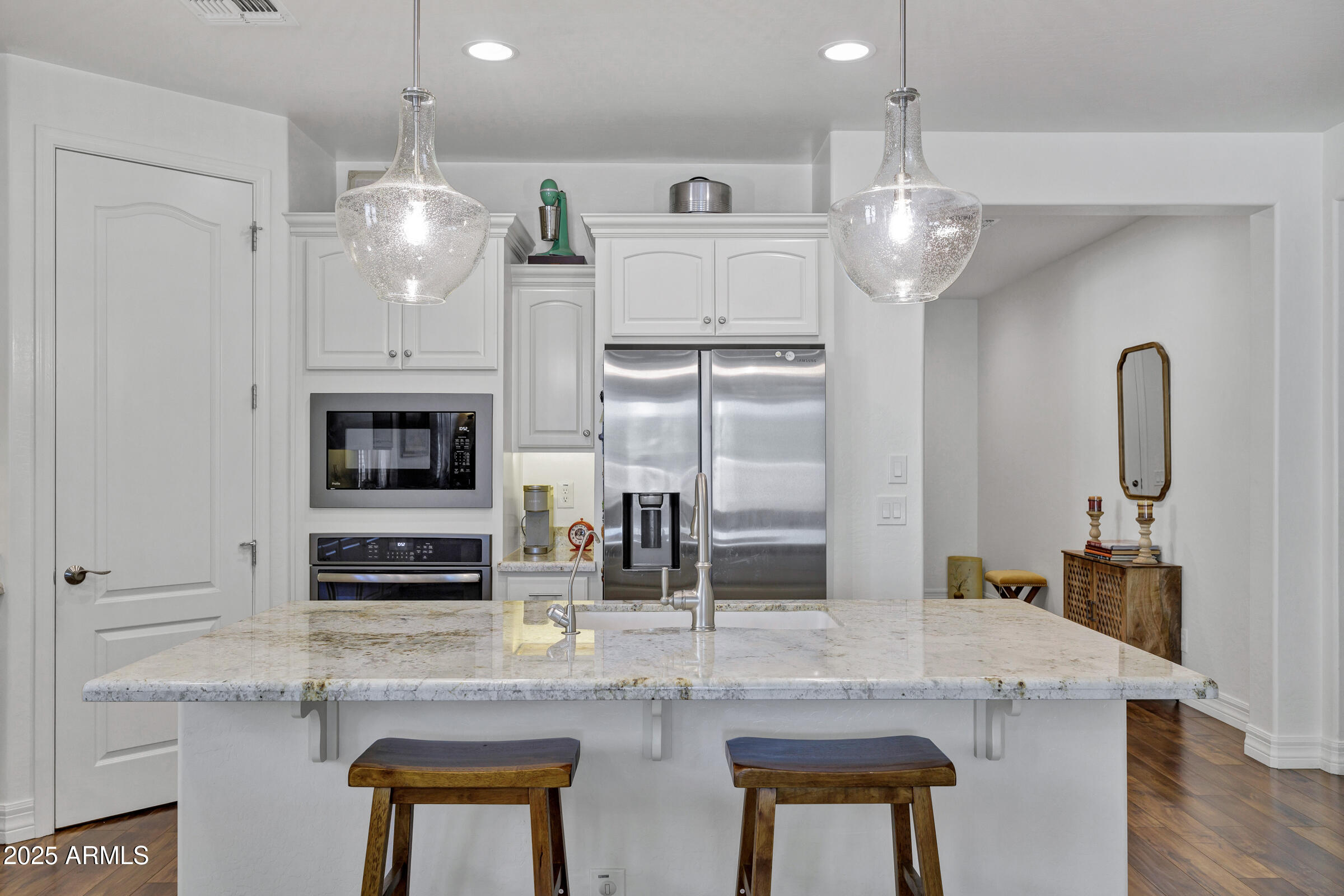 4410 South Intensity Mesa, AZ 85212 - Photo 10 of 28 a kitchen with stainless steel appliances kitchen island granite countertop a table chairs in it and wooden floors