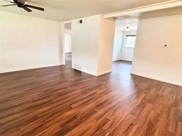 a view of a room with wooden floor and a ceiling fan