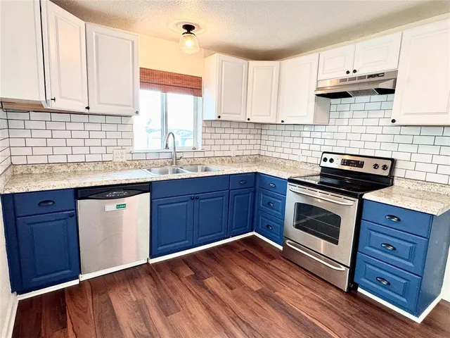 a kitchen with granite countertop wooden cabinets appliances and a window