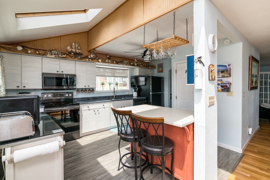262 Manomet Point Road Plymouth, MA 02360 - Photo 7 of 40 a kitchen with stainless steel appliances kitchen island granite countertop a refrigerator a stove top oven a sink dishwasher and chairs with wooden floor