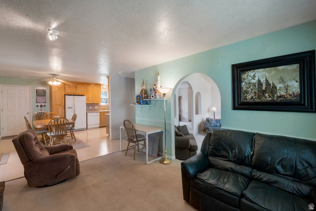 11072 Windy Peak Ridge Drive, Unit 32 Sandy, UT 84094 - Photo 11 of 30 Open-concept living area featuring light-toned carpet and a spacious kitchen with wood cabinetry and white appliances