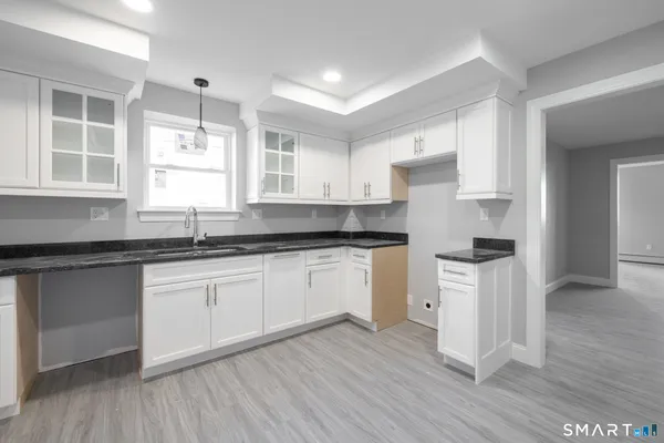 a kitchen with granite countertop a sink cabinets and wooden floor