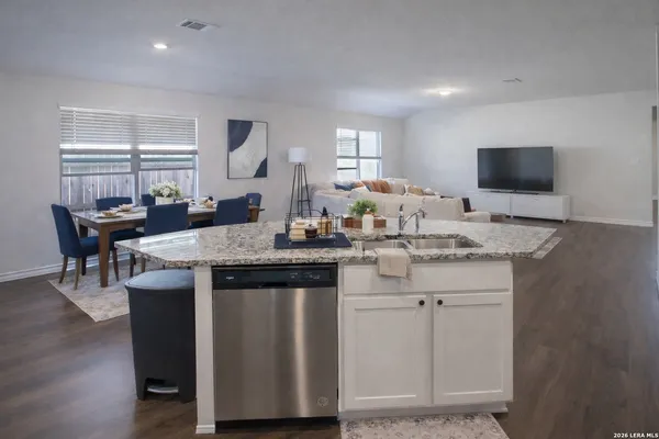 a kitchen with granite countertop a sink cabinets and wooden floor