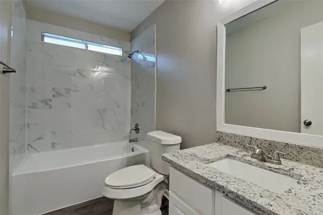 a bathroom with a granite countertop sink toilet and shower