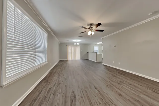 a view of an empty room with a window and wooden floor