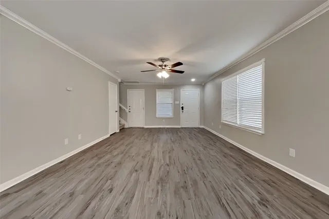 a view of an empty room with a window and wooden floor