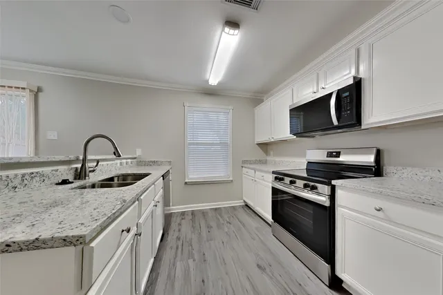 a kitchen with stainless steel appliances granite countertop a stove a sink and a microwave