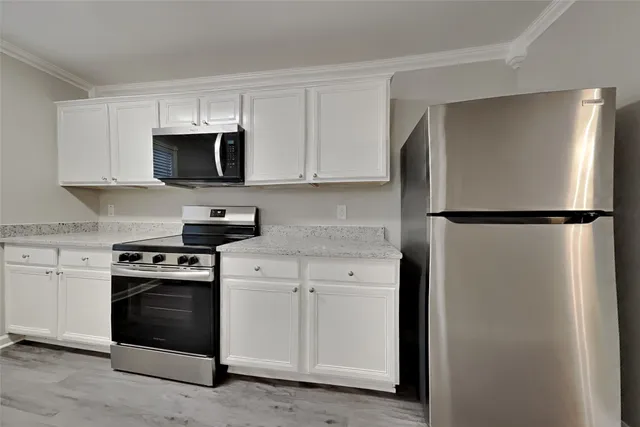 a kitchen with a refrigerator stove and white cabinets