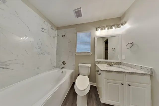 a bathroom with a granite countertop sink toilet a large mirror a bathtub and shower