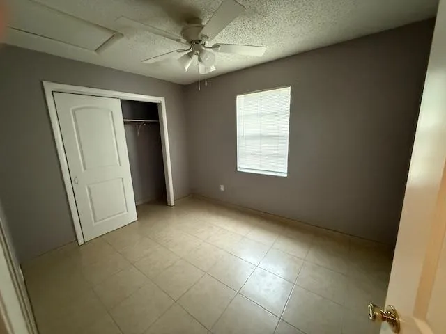 an empty room with windows and fan